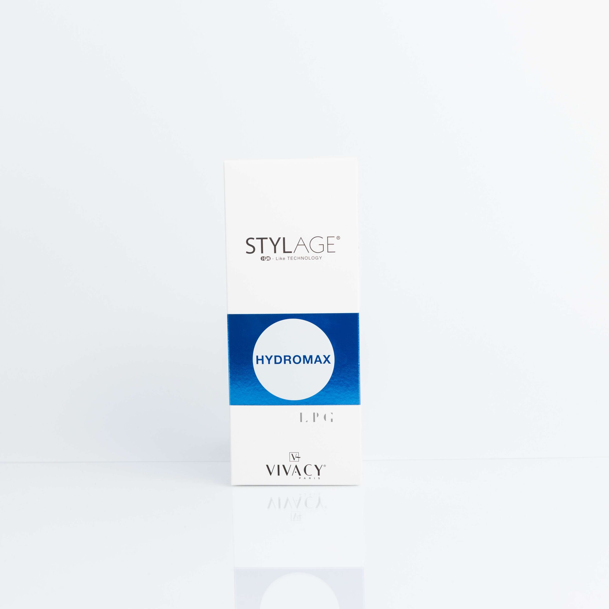 The image shows a white rectangular product box standing upright on a reflective white surface against a plain white background. The branding and text on the box are as follows: Top section (gray band): "STYLAGE®" in bold black uppercase letters, with smaller text below it reading "by VIVACY LABORATORIES". Middle section (blue circular badge): "HYDROMAX" in white uppercase letters on a gradient blue circle. Bottom section (white): "1 x 1 ml" in small black text, indicating the product volume. Footer (white with logo): The "VIVACY" logo in black, consisting of a stylized "V" icon followed by the brand name in uppercase. This is a cosmetic or medical product from the Stylage line by Vivacy Laboratories, specifically the "Hydromax" variant, which is typically a hyaluronic acid-based dermal filler or skin booster designed for hydration and biorevitalization. The packaging is minimalist and professional, common for aesthetic medicine products